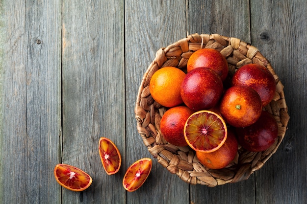 Frische reife sizilianische Orangen und geschnittene Stücke auf einem alten Holztisch. Selektiver Fokus. Draufsicht.