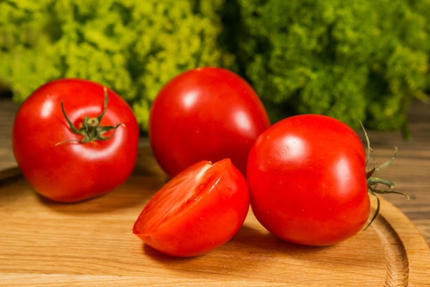 Frische reife Tomaten auf einem Holztisch mit einem grünen Salat