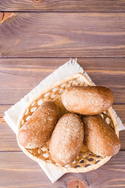 Frische Roggenbrötchen in einem Korb auf einem Holztisch