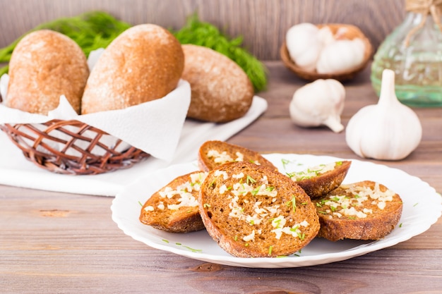 Frische roggenknoblauchcroutons mit dill auf einer platte auf einem holztisch