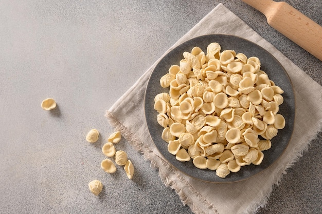 Frische rohe apulische Pasta Orecchiette aus Vollkornmehl auf einer dunklen Tischplatte