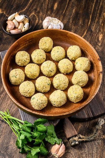 Frische rohe Falafelbällchen in einem Holzteller.