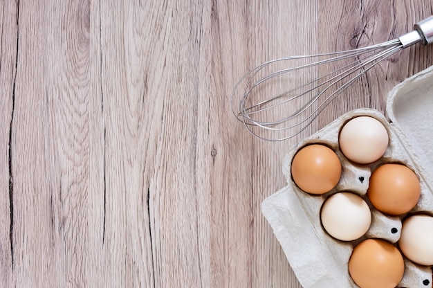 Frische rohe Hühnereier im Eierkarton des Kartons auf hölzernem Hintergrund. Die Draufsicht auf braune und weiße Eier.