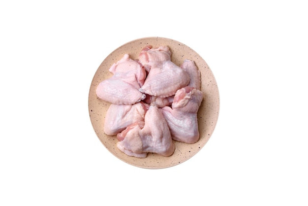 Frische rohe Hühnerflügel mit Salz und Gewürzen, die zum Backen auf einem dunklen Betongrund zubereitet wurden