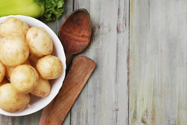 Frische rohe Kartoffeln in der Schüssel, rustikaler Holztisch.