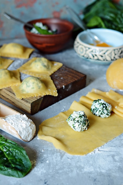 Frische rohe Ravioli mit Ricotta und Spinat auf einem blauen Hintergrund.