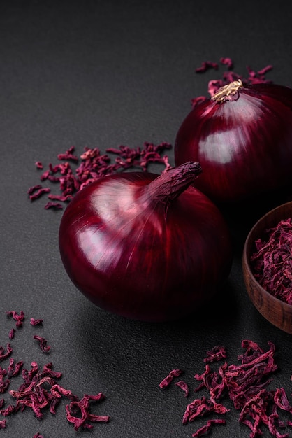 Frische rohe rote Zwiebel auf dunklem strukturiertem Betonhintergrund