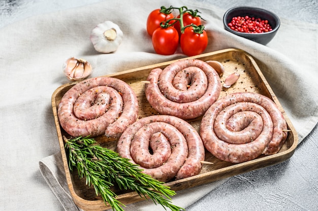 Frische rohe Spiralschweinwürste auf einem Holztablett