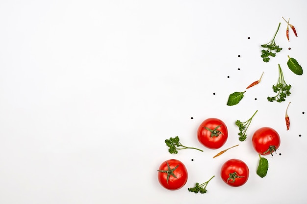 Frische rohe Tomaten und grüne Kräuter auf weißem Hintergrund mit Kopienraum. Bio-Gemüse auf Weiß