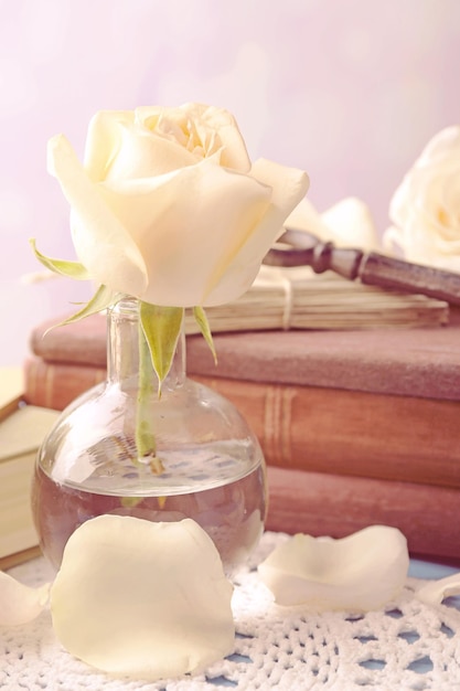 Frische Rosen mit altem Buch und Buchstaben auf farbigem Holztisch, auf hellem Hintergrund. Vintage-Konzept