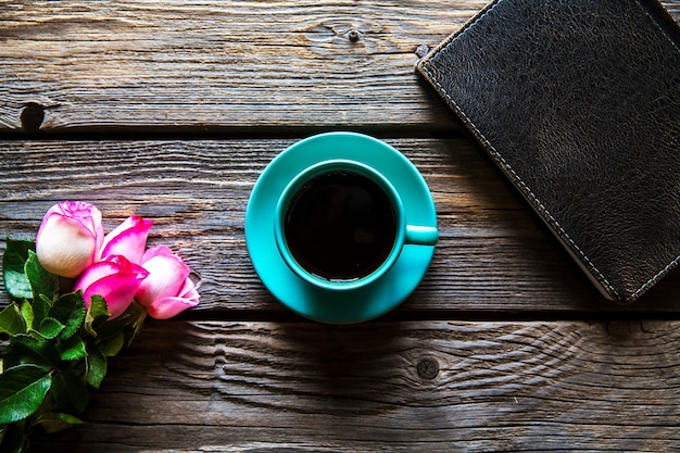 Frische Rosen mit Tagebuch und Tasse Kaffee auf Holztisch