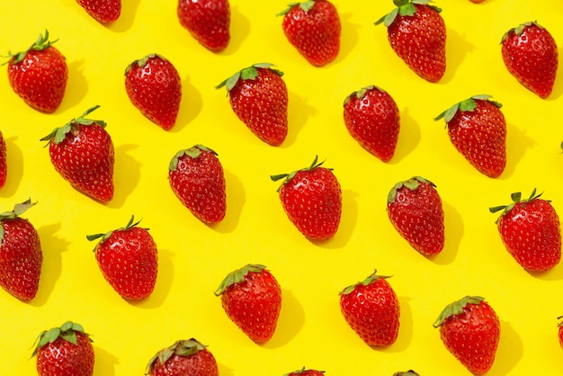 Frische rote Erdbeere lokalisiert auf gelbem Hintergrund, Draufsicht. Minimalistisches Erdbeermuster