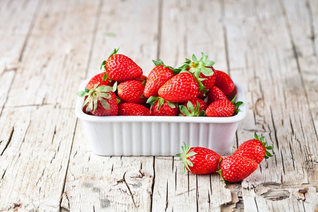 Frische rote Erdbeeren in der weißen Schüssel und in den tadellosen Blättern