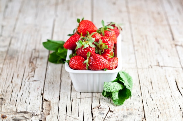 Frische rote Erdbeeren in der weißen Schüssel und in den tadellosen Blättern