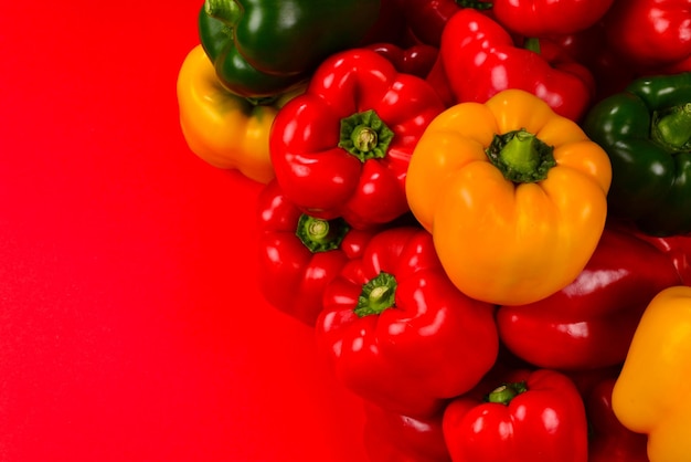 Frische rote gelbe grüne Paprika auf rotem Grund