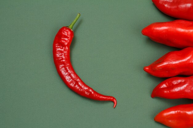 Frische rote heiße und grüne Paprika auf grünem Hintergrund. Ansicht von oben.