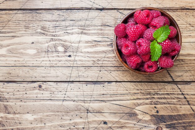 Frische rote Himbeerbeeren in einer hölzernen Platte.