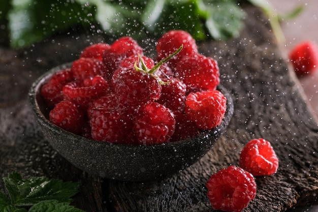 Frische rote Himbeeren in Schüssel auf dunklem Holztisch. Closeup Beeren Hintergrund.