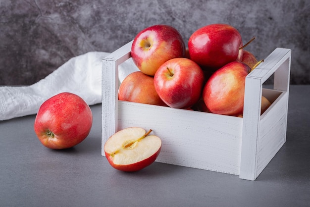 Frische rote Äpfel in einer Holzkiste auf grauem Hintergrund Bio-Lebensmittel