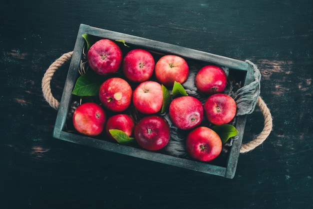 Frische rote Äpfel in einer Holzkiste Bio-Lebensmittel auf schwarzem Hintergrund Ansicht von oben Freier Platz für Text