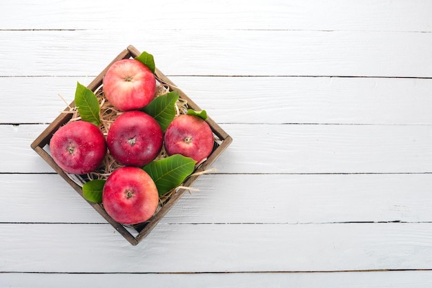 Frische rote Äpfel in einer Holzkiste Bio-Lebensmittel auf weißem Hintergrund aus Holz Draufsicht Freier Platz für Text