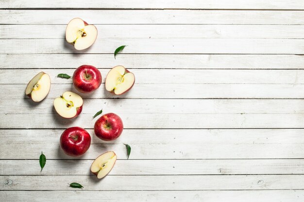 Frische rote Äpfel mit Blättern. Auf einem weißen Holztisch.