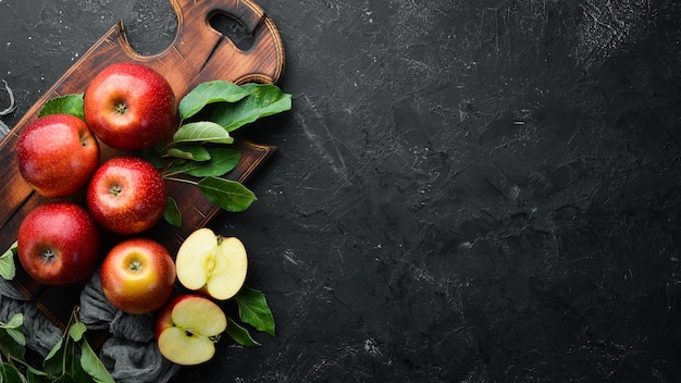 Frische rote Äpfel mit grünen Blättern auf schwarzem Hintergrund Früchte Draufsicht Freier Platz für Text