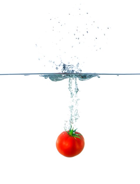 Frische rote Tomatenfrucht, die im Wasser sinkt