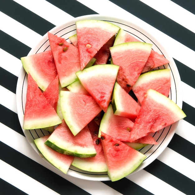 Frische rote Wassermelonenscheibe in Platte auf gestreiftem Hintergrund Sommerkonzept Draufsicht Flaches Bild