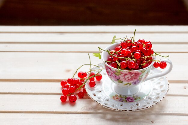 Frische saftige Beeren der roten Johannisbeere in der Schale auf einem Holztisch im Garten im Sommer Beere