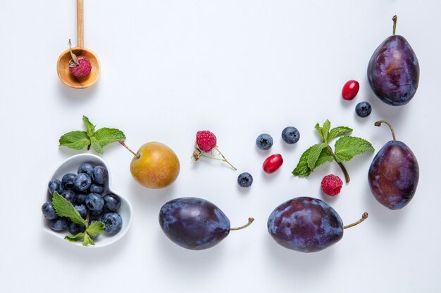 Frische saftige Beeren und Früchte auf einem weißen Brett.