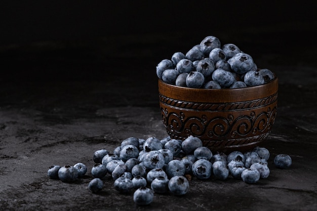 Frische saftige Blaubeeren in der Schüssel auf dem schwarzen Hintergrund Zurückhaltende Fotografie Hochwertiges Foto