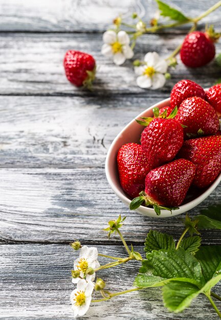 Frische saftige Erdbeeren mit Blättern auf einer Schüssel