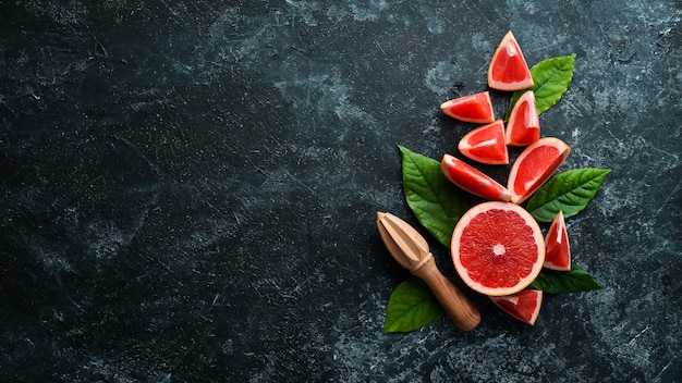 Frische saftige Grapefruit mit Blättern Zitrusfrüchte auf schwarzem Steinhintergrund Draufsicht Freier Kopierplatz