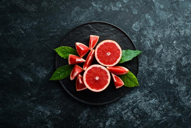 Frische saftige Grapefruit mit Blättern Zitrusfrüchte auf schwarzem Steinhintergrund Draufsicht Freier Kopierplatz