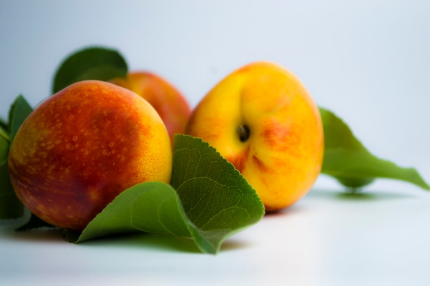 Frische saftige Nektarine mit grünen Blättern auf weißem