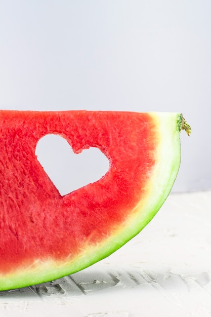 Frische saftige Wassermelonenscheibe mit Herzformloch auf weißem Hintergrund. Valentinstag, Liebe, Sommerkonzept mit Kopierraum