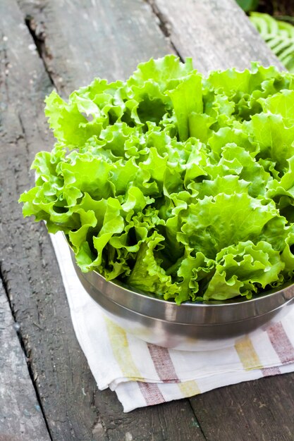 Frische Salatblätter in der Metallschale auf altem Holztisch