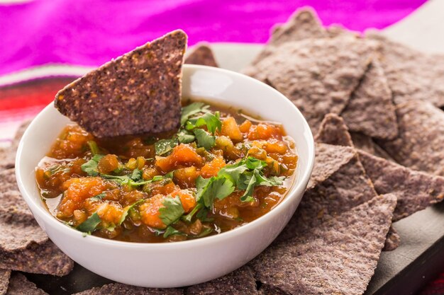 Foto frische salsa in weißer schüssel mit blauen maistortilla-chips.