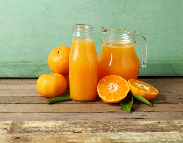 Frische Scheibe Orange und Flasche Saft auf hölzernem Hintergrund