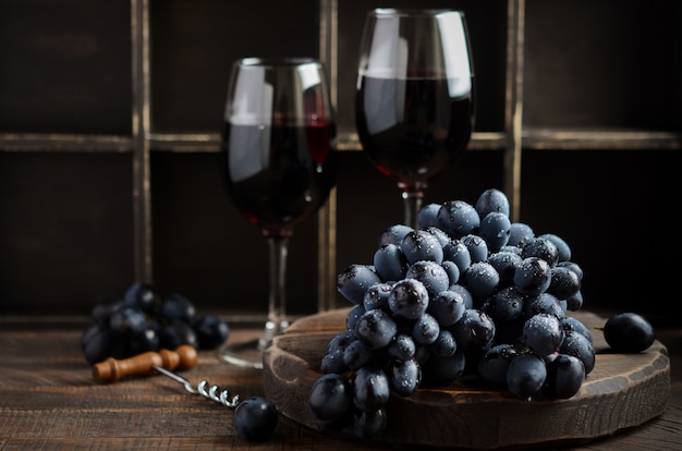 Frische schwarze Trauben und Rotwein auf Holztisch