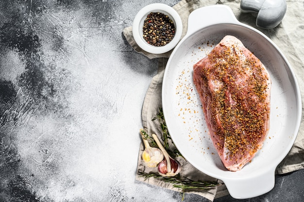 Frische Schweinefleischstücke. Rohes Fleisch mit Gewürzen. Grauer Hintergrund. Ansicht von oben