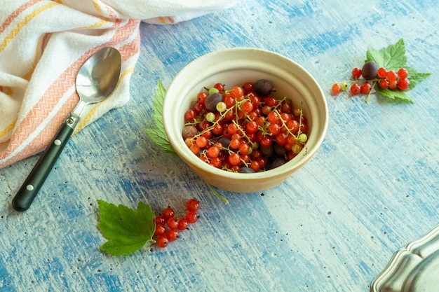 Frische Sommerbeeren in einem Teller auf Holzhintergrund Rote Johannisbeeren und Stachelbeeren aus dem Garten.