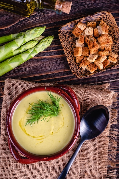 Frische Spargelcremesuppe und Zutaten auf Holztisch, selektiver Fokus