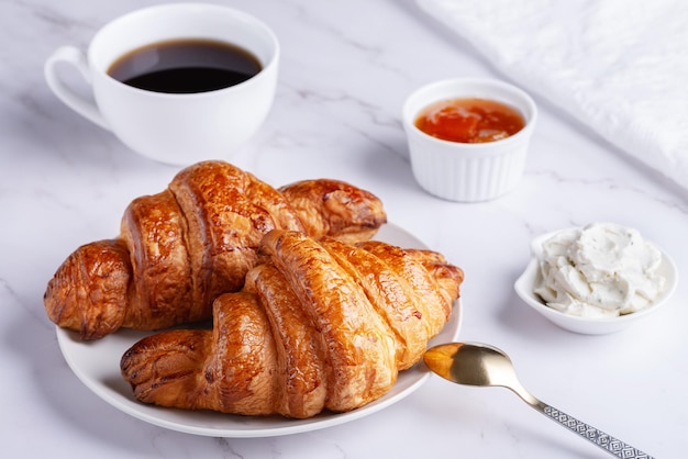 Frische süße Croissants mit Hüttenkäse und Aprikosenmarmelade zum Frühstück Kontinentales Frühstück