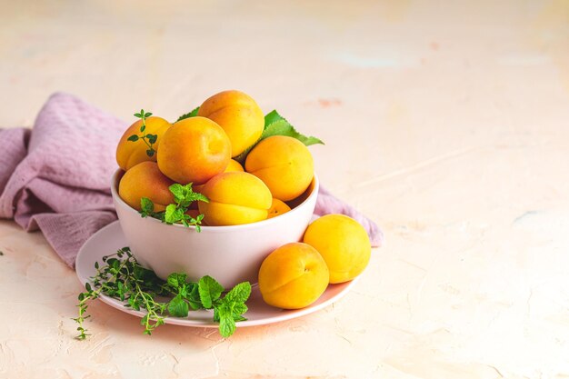 Frische, süße, gelb-orangefarbene Aprikosen in einer rosa Schüssel auf dem rosafarbenen Betonoberflächentisch, selektiver Fokus, geringe Tiefe der Felder