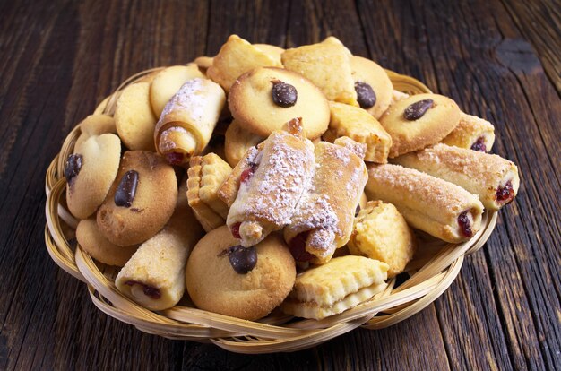 Frische süße Kekse in einem Korbteller auf altem Holztisch