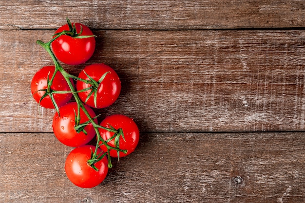 Frische Tomaten auf einem Zweig auf einem strukturierten Holz