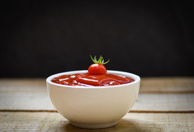 Frische Tomaten auf Ketschup in der Schalentomatensauce auf hölzernem Hintergrund