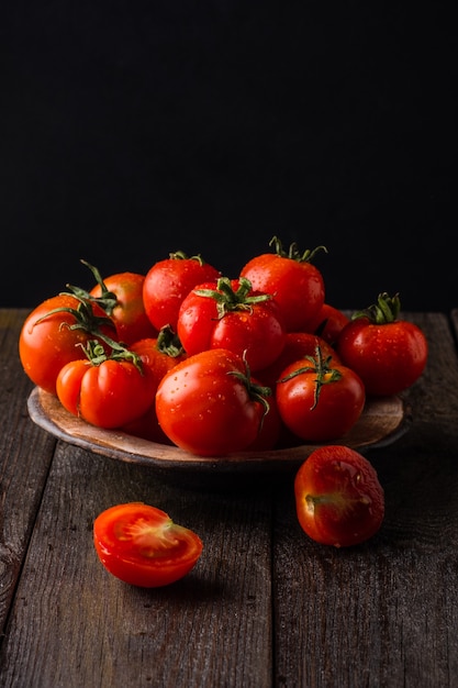 frische Tomaten in einem Teller auf dunklem Hintergrund Tomaten ernten